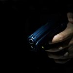 Rooftop Shooter Masqueraded As Senator Hand holding a handgun in low light