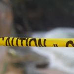Yellow caution tape stretched across a blurred outdoor scene