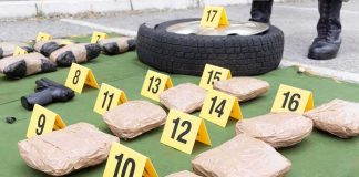 Evidence markers with wrapped packages, tire, and handgun at a crime scene