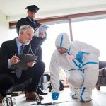 Forensic investigator collects evidence as police and detective observe