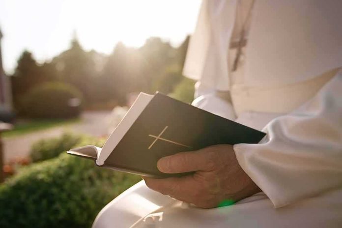 Person in white robe holding a Bible outdoors