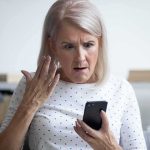 Older woman looking shocked at a smartphone