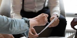 Jobs Whiplash: August Jumps, Trust Wobbles Hands of colleagues discussing a document during a meeting