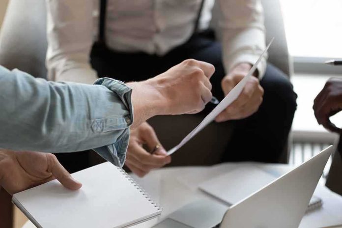 shutterstock_1575793039 Hands of colleagues discussing a document during a meeting