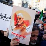 Protesters holding posters of Qasem Soleimani and Abu Mahdi al-Muhandis