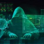 Hooded hacker at computer with digital virus graphics