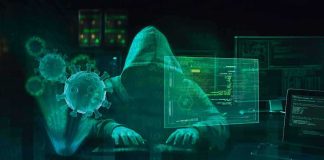 Hooded hacker at computer with digital virus graphics