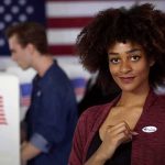 Voter showing an I Voted sticker at a polling place