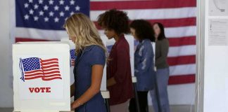 Voters at booths with American flags in a polling place