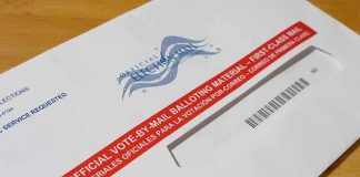 Mail-in ballot envelope with red label on wooden table