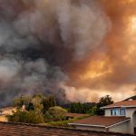 Wildfire smoke billows over suburban houses
