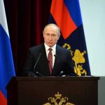 speaker at podium with flags in background