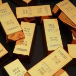 Gold bars stacked and scattered on a dark surface