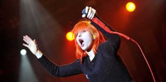 Singer with bright orange hair performing on stage