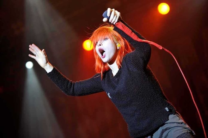 Singer with bright orange hair performing on stage