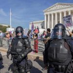 Riot police stand in front of a courthouse during a protest