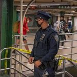 Police officer stands in a subway station near caution tape