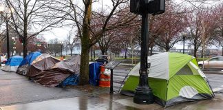 Tents lined along a wet city sidewalk on a rainy day