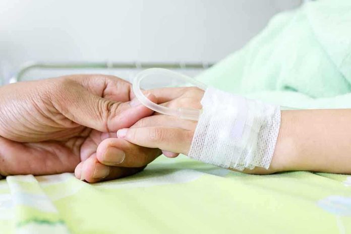 shutterstock_215457235 A person holding the hand of a patient with an IV in a hospital bed