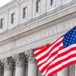 American flag waves in front of a United States courthouse facade