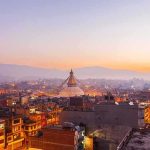 Buddhist stupa rising over a city at dusk
