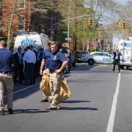 Police officers and investigators at a blocked city street scene