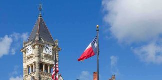 Historic stone courthouse with clock tower and flags