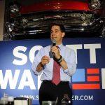 man speaking into a microphone at a campaign-style event