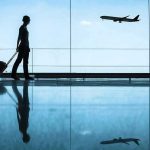 Traveler with rolling suitcase in airport terminal
