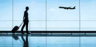 Traveler with rolling suitcase in airport terminal