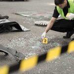 Forensic investigator marking evidence at crash scene