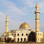 Mosque Expansion Sparks Divide Mosque with golden dome and two tall minarets under a partly cloudy sky