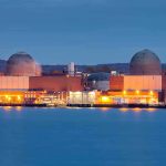 nuclear power plant with two domed reactor buildings by water at dusk