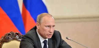 Vladimir Putin speaking at a meeting with documents and a microphone