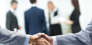 Businessmen handshake over a glass desk
