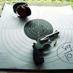 Revolver and ear protection on paper shooting target