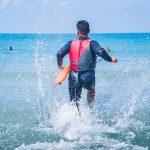 lifeguard wading into ocean with rescue buoy