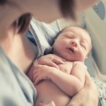 newborn baby sleeping in a parent's arms