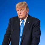 Donald Trump at a podium against a blue background