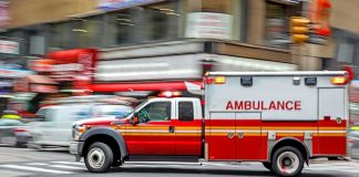 Ambulance speeding through a city intersection with lights on
