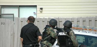 police officers in tactical gear beside patrol car