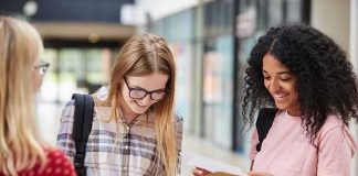 Florida Universities Face Major Admissions Shift Students smiling while reading papers in a school hallway