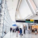 Airport terminal hallway with travelers and signage