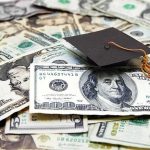 Graduation cap on a pile of US dollar bills