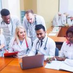 Group of medical students collaborating around a laptop