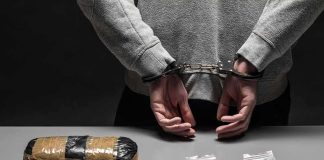 person in handcuffs behind back over table with seized packages