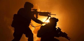 Homecoming Game Turns Violent, Suspect Released Two armed soldiers silhouetted against fiery smoke