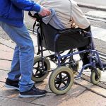 Caregiver pushing person in wheelchair over curb