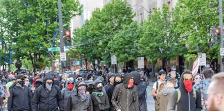 group of masked protesters walking through a city street