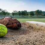 Softball and glove near a base on a dirt field